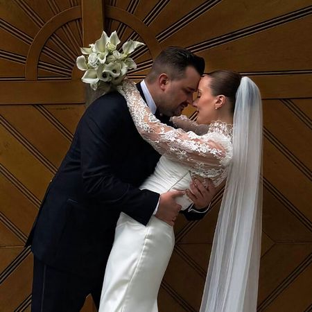 Heiraten im Schloß Styrum: Ein Hochzeitspaar umarmt sich glücklich und verliebt vor einem romantischen Tor aus dunklem Holz.